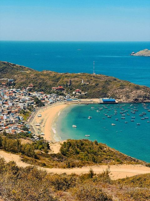 A seaside town on a curved bay under a bright sky — shot on B KCX