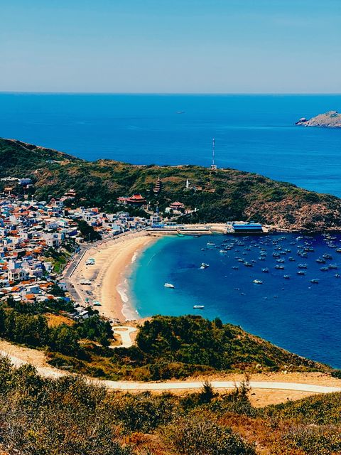 Hilltop view over a fishing village and crescent beach — shot on ELEV MAPLE