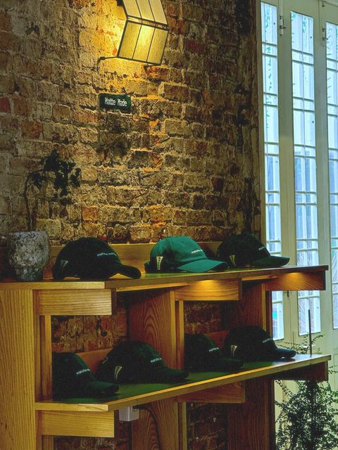 Caps lined up on wooden shelves against a warm-lit brick wall — shot on ELEV 03