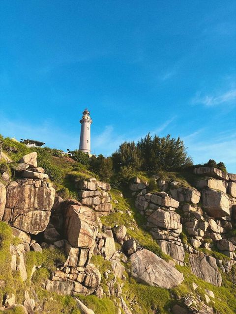 A white lighthouse on a rocky hill above the sea — shot on A PYX